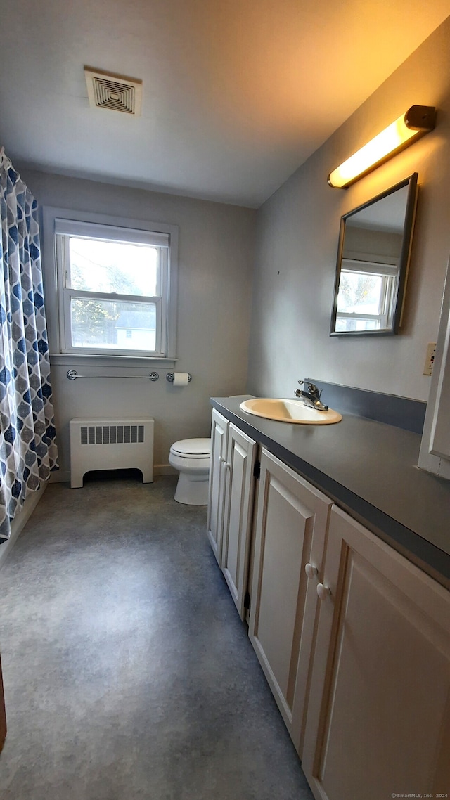 bathroom with concrete flooring, radiator heating unit, a shower with curtain, vanity, and toilet