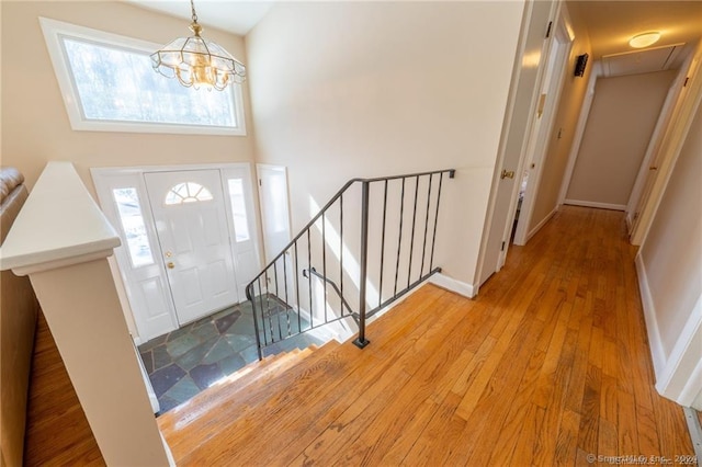 entryway with a towering ceiling, a chandelier, and light hardwood / wood-style floors