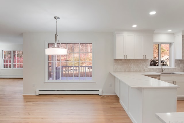 kitchen featuring light hardwood / wood-style flooring, white cabinetry, sink, decorative light fixtures, and a baseboard heating unit