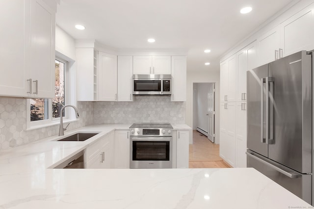 kitchen featuring light stone counters, sink, white cabinets, and stainless steel appliances