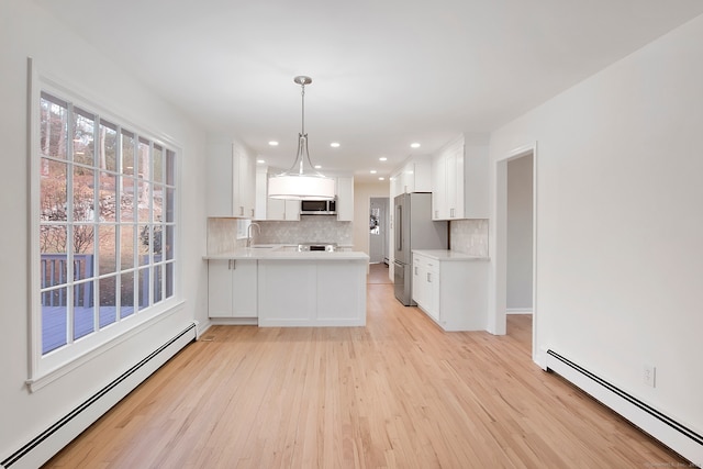 kitchen featuring kitchen peninsula, stainless steel appliances, white cabinetry, and a baseboard heating unit