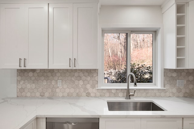 kitchen featuring backsplash, light stone counters, white cabinetry, and sink