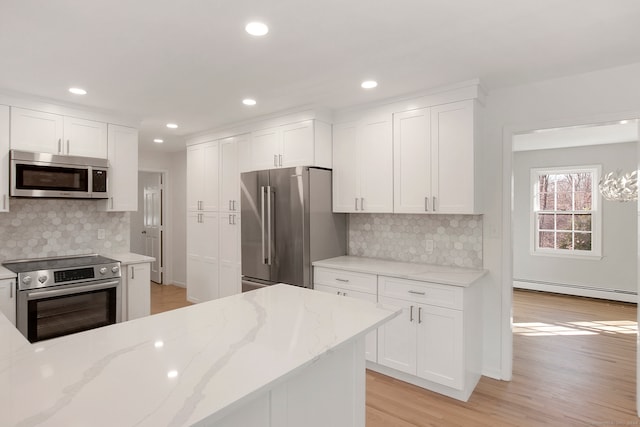 kitchen with tasteful backsplash, stainless steel appliances, a baseboard heating unit, light hardwood / wood-style floors, and white cabinetry