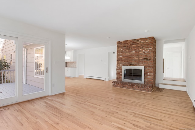 unfurnished living room with a brick fireplace, baseboard heating, and light hardwood / wood-style floors