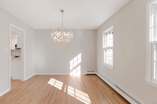 unfurnished dining area with a baseboard radiator, light wood-type flooring, and an inviting chandelier