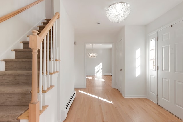 foyer with light hardwood / wood-style flooring, a baseboard heating unit, and an inviting chandelier