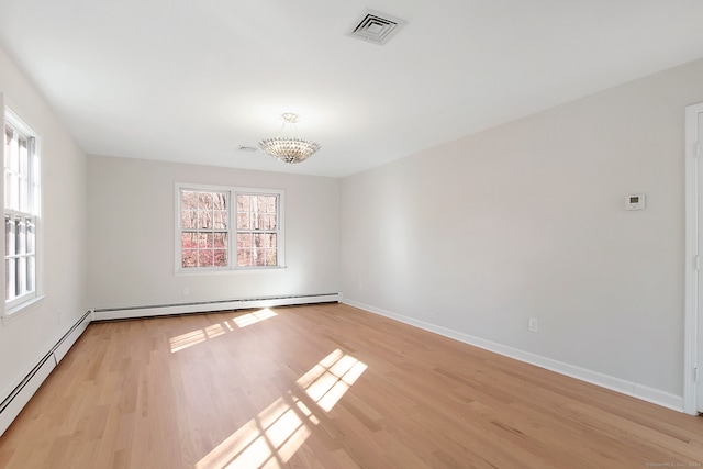 spare room with light hardwood / wood-style flooring, an inviting chandelier, and a baseboard heating unit