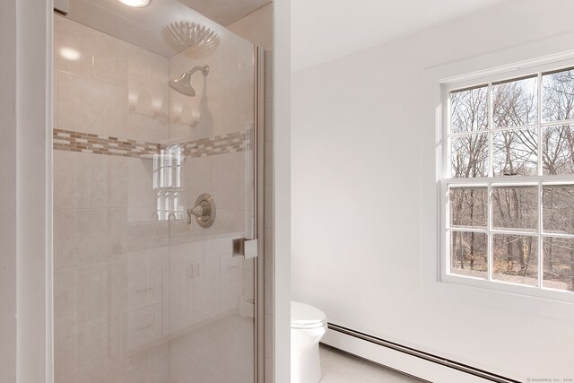 bathroom featuring a healthy amount of sunlight, toilet, a shower with shower door, and a baseboard heating unit