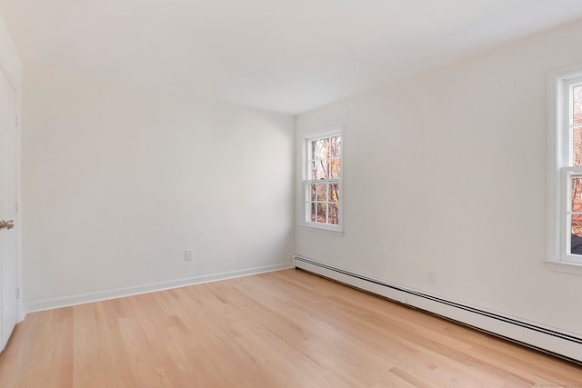 spare room with a baseboard heating unit, light hardwood / wood-style floors, and plenty of natural light