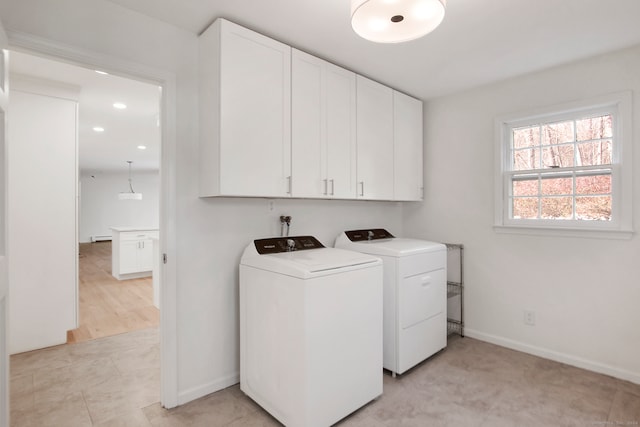 washroom featuring washer and clothes dryer, cabinets, and light wood-type flooring