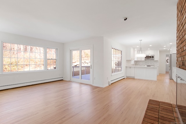 unfurnished living room with sink, a baseboard radiator, and light hardwood / wood-style floors