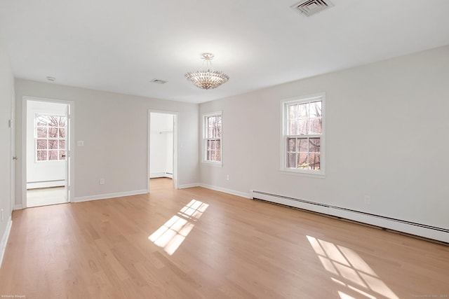 empty room featuring a baseboard radiator, light hardwood / wood-style flooring, and plenty of natural light