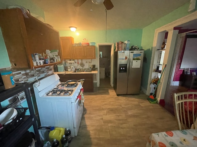 kitchen with gas range gas stove, stainless steel fridge with ice dispenser, ceiling fan, and tasteful backsplash