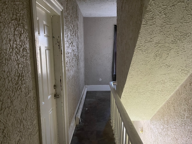 hallway featuring a textured ceiling and dark tile patterned floors