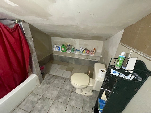 bathroom featuring toilet, shower / bath combo with shower curtain, and tile patterned floors