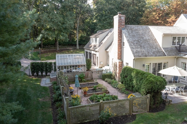exterior space with fence, a garden, a patio area, and a chimney