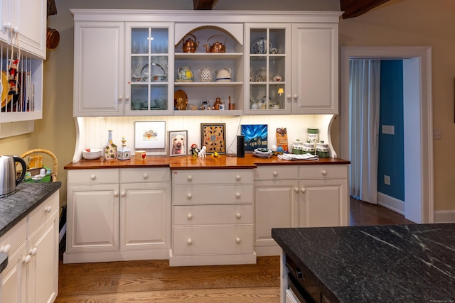 bar with dark hardwood / wood-style floors, white cabinetry, and dark stone countertops