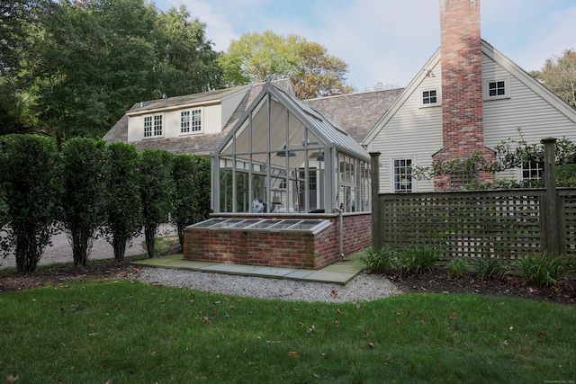 rear view of property with a yard, a chimney, and a sunroom