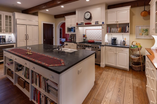 kitchen with dark countertops, appliances with stainless steel finishes, open shelves, and light wood-type flooring