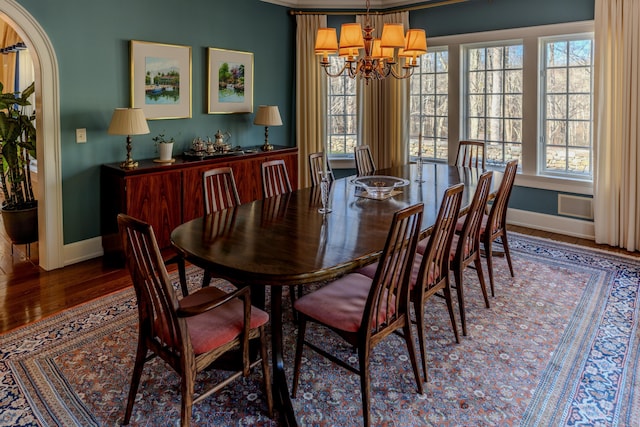 dining space with hardwood / wood-style flooring, crown molding, and a notable chandelier