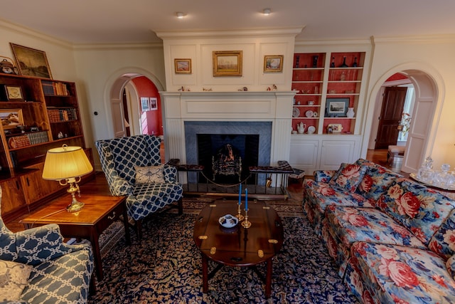 living room featuring crown molding, arched walkways, built in features, and a fireplace