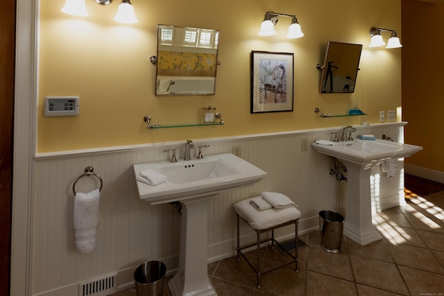 bathroom with a sink, tile patterned floors, wainscoting, and visible vents