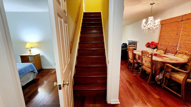 stairs with wood-type flooring and a chandelier