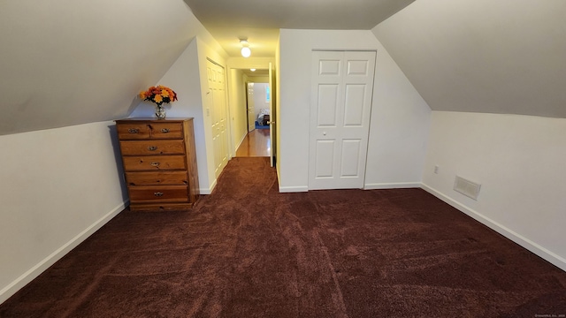 additional living space featuring dark colored carpet and lofted ceiling