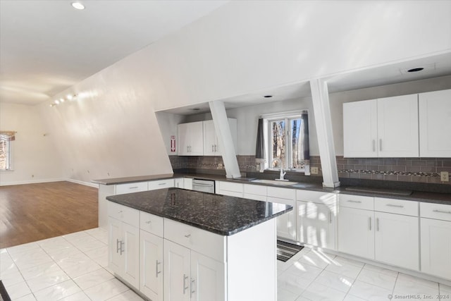 kitchen with white cabinetry, decorative backsplash, light hardwood / wood-style floors, and sink