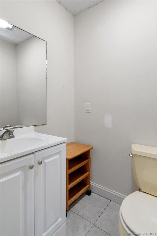 bathroom with toilet, vanity, and tile patterned floors