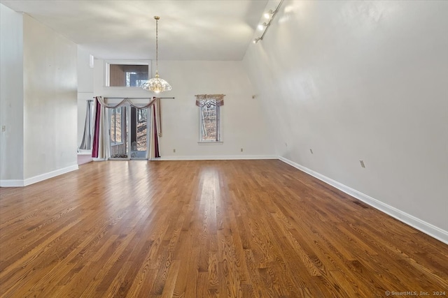 interior space featuring lofted ceiling, hardwood / wood-style flooring, and rail lighting