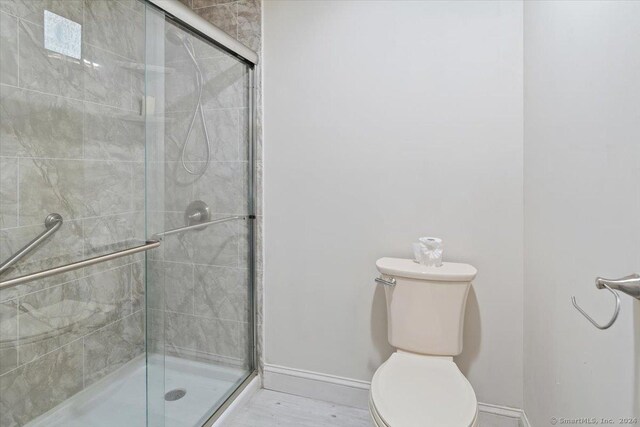 bathroom featuring toilet and a shower with shower door