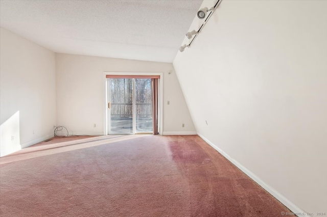 carpeted spare room with a textured ceiling and lofted ceiling