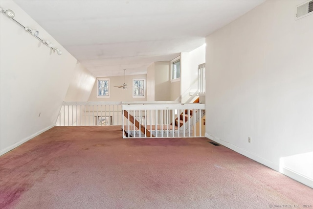 interior space featuring ceiling fan, vaulted ceiling, and carpet floors