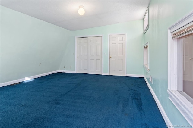 unfurnished bedroom featuring dark colored carpet and multiple closets