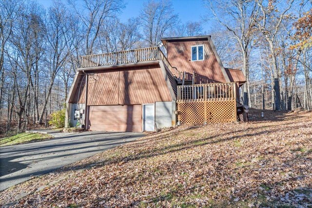 rear view of property featuring a garage and a wooden deck