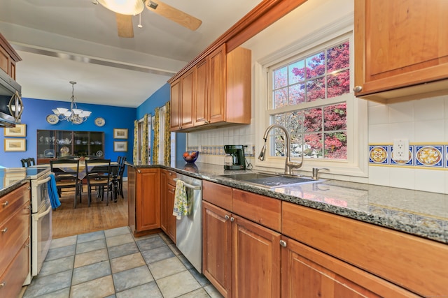 kitchen featuring backsplash, sink, dark stone countertops, light wood-type flooring, and appliances with stainless steel finishes