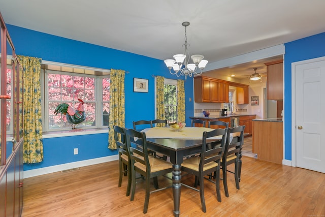 dining space featuring ceiling fan with notable chandelier, light hardwood / wood-style floors, and sink