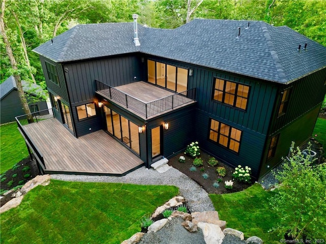 rear view of house featuring a balcony and a yard