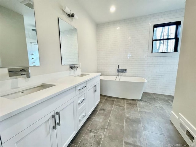 bathroom with a bath, vanity, and tile walls