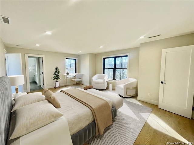 bedroom with ensuite bathroom and light wood-type flooring