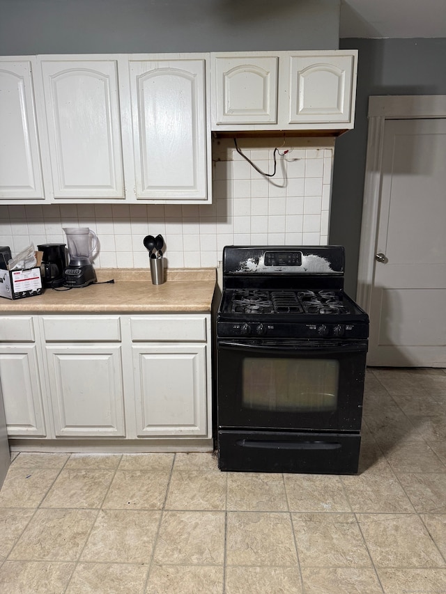 kitchen featuring white cabinets, black range with gas stovetop, and backsplash