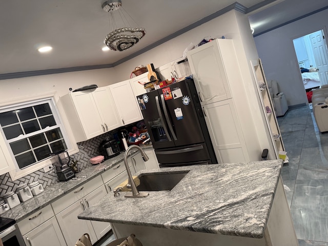 kitchen with refrigerator with ice dispenser, sink, backsplash, light stone countertops, and white cabinetry