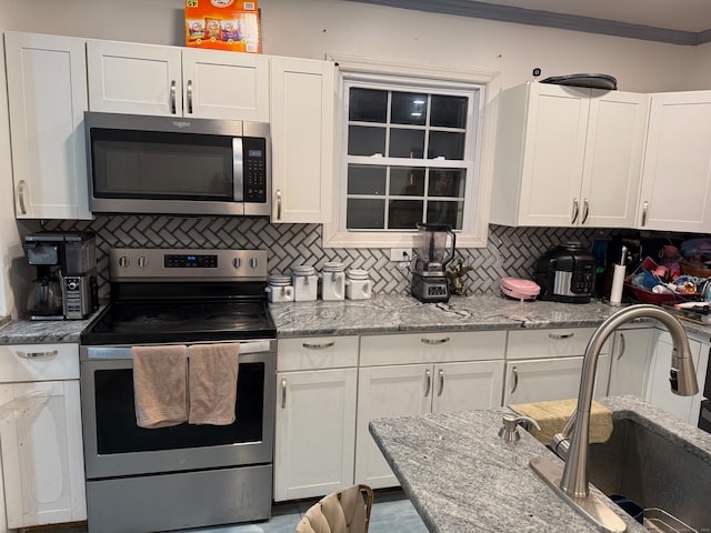 kitchen with white cabinets, appliances with stainless steel finishes, sink, and tasteful backsplash