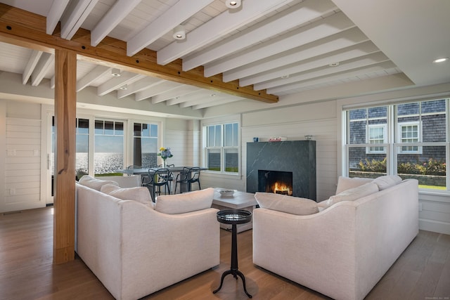 living room featuring beamed ceiling, a fireplace, and wood-type flooring