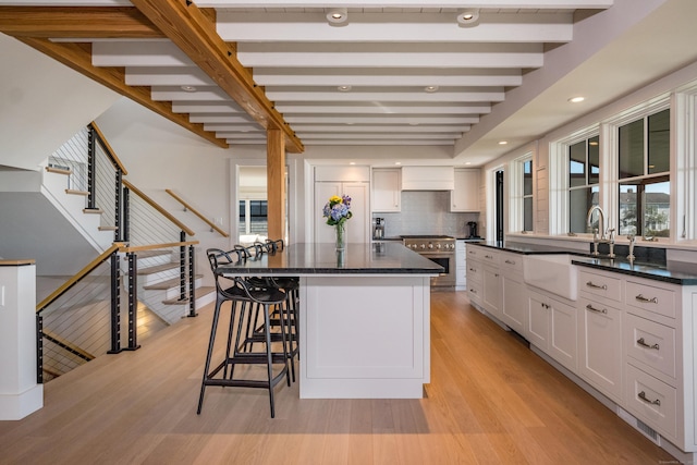 kitchen with sink, high end stainless steel range oven, white cabinetry, and a center island