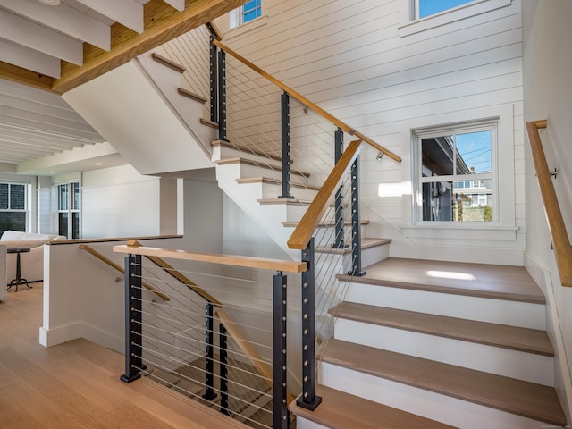 staircase featuring beam ceiling and hardwood / wood-style floors