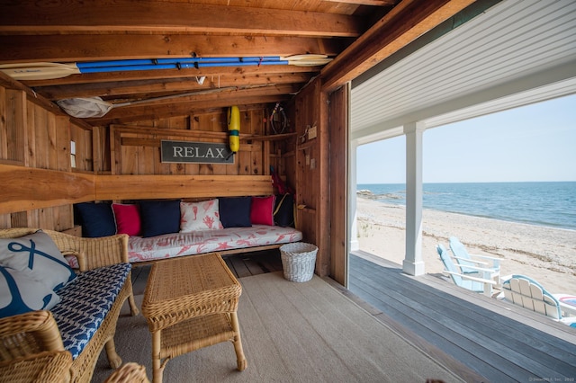 interior space featuring wood walls, lofted ceiling with beams, a view of the beach, and a water view