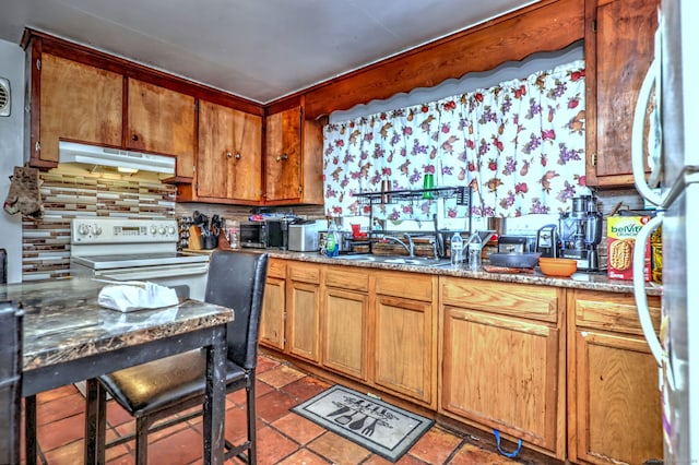 kitchen with electric range, backsplash, stainless steel fridge, and sink