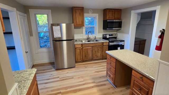 kitchen with a wealth of natural light, sink, light hardwood / wood-style flooring, and appliances with stainless steel finishes